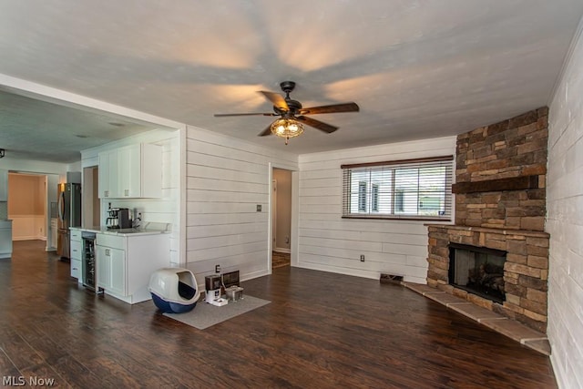 unfurnished living room with a fireplace, dark hardwood / wood-style flooring, wine cooler, and ceiling fan