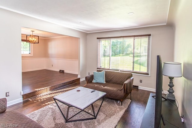 living room featuring crown molding, plenty of natural light, dark wood-type flooring, and a notable chandelier