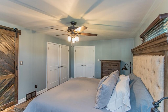 carpeted bedroom with a barn door and ceiling fan