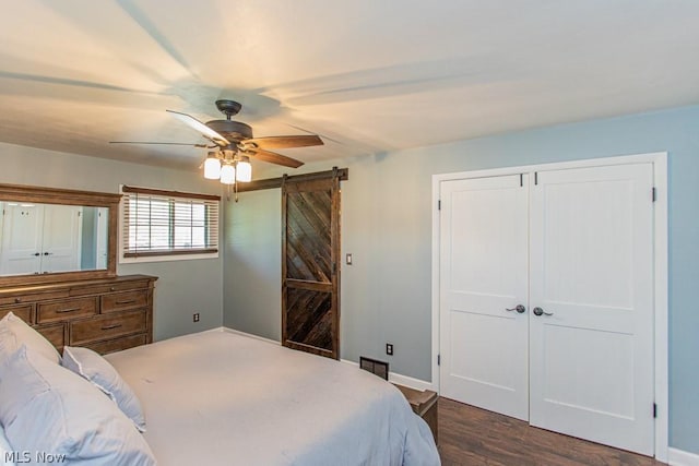 bedroom featuring a barn door, ceiling fan, and dark hardwood / wood-style floors