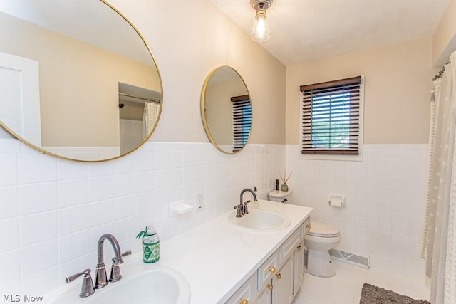 bathroom featuring tile patterned flooring, vanity, toilet, and tile walls