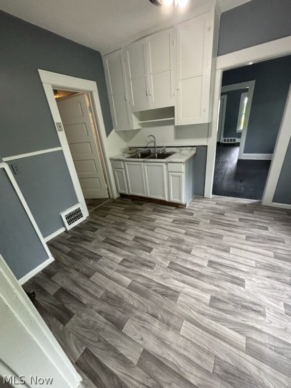 kitchen featuring sink, white cabinetry, and light wood-type flooring