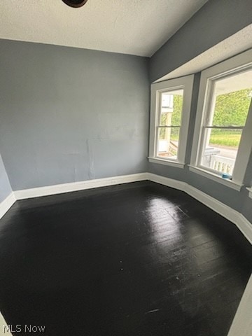 unfurnished room with a textured ceiling and hardwood / wood-style floors