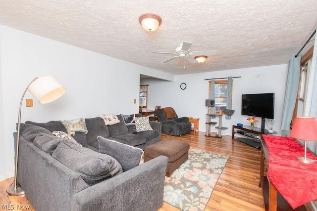 living room with hardwood / wood-style flooring, ceiling fan, and a textured ceiling