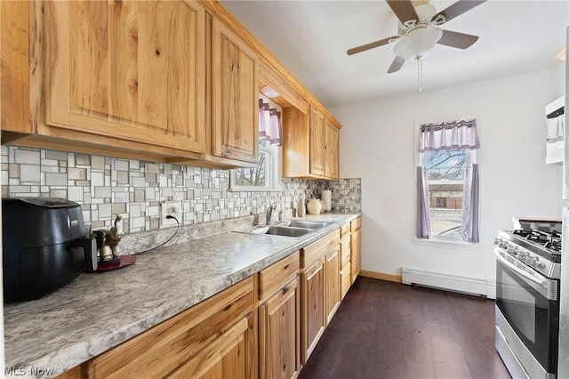 kitchen featuring ceiling fan, backsplash, baseboard heating, stainless steel gas stove, and sink