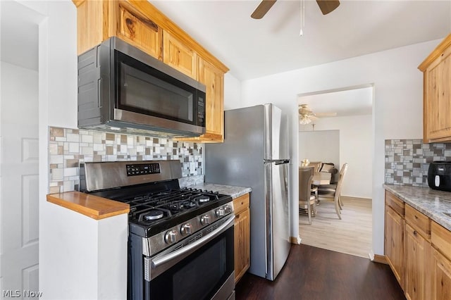 kitchen with ceiling fan, decorative backsplash, stainless steel appliances, dark hardwood / wood-style flooring, and light stone counters