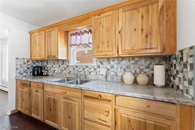 kitchen with a baseboard heating unit, dark wood-type flooring, backsplash, and sink