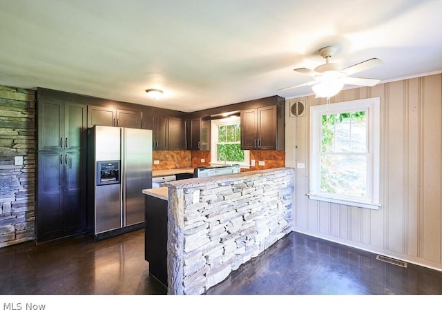 kitchen featuring stainless steel refrigerator with ice dispenser, a wealth of natural light, backsplash, and kitchen peninsula