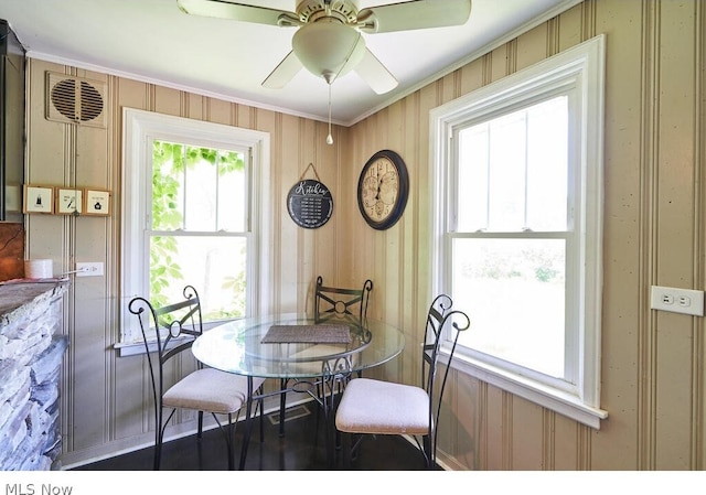 dining room featuring wood walls, hardwood / wood-style flooring, and ceiling fan