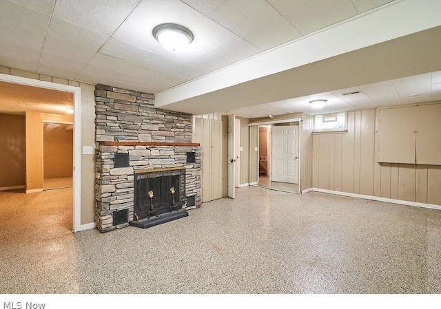 basement featuring a stone fireplace and a drop ceiling