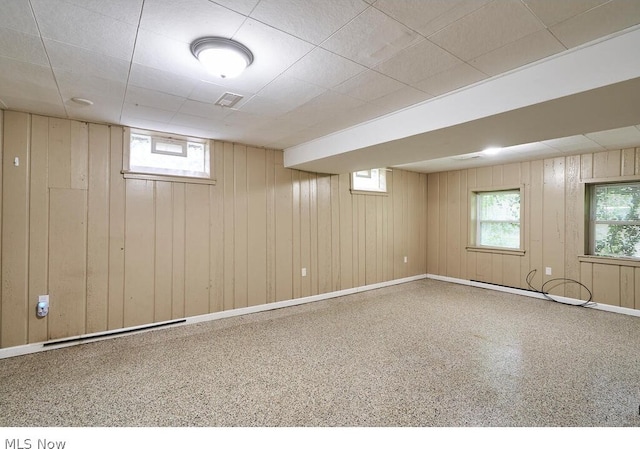 basement featuring wooden walls and a drop ceiling