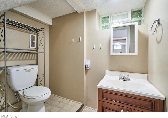 bathroom with a textured ceiling, tile flooring, oversized vanity, and toilet