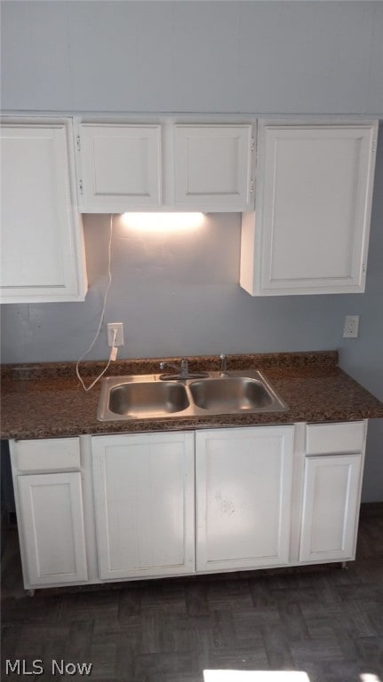 kitchen with dark hardwood / wood-style floors, white cabinetry, and sink