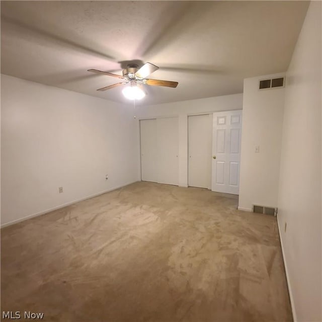 spare room with light carpet, ceiling fan, and visible vents