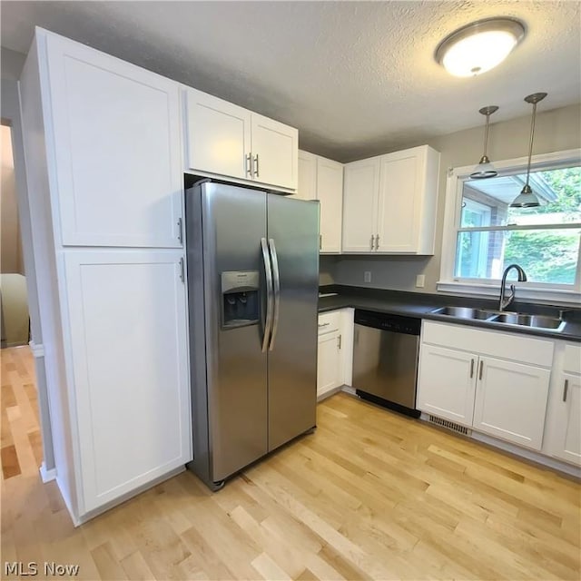 kitchen featuring dark countertops, white cabinetry, appliances with stainless steel finishes, and a sink