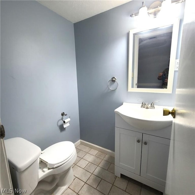 half bath featuring tile patterned flooring, baseboards, vanity, and toilet