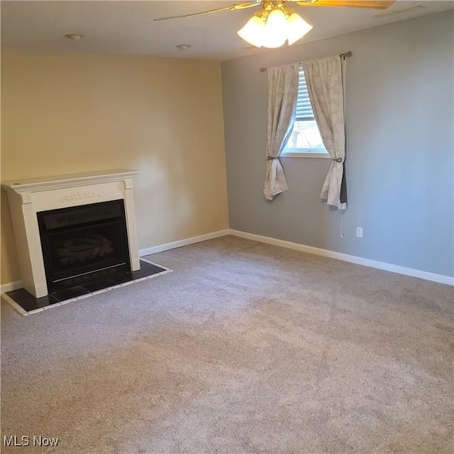 unfurnished living room with ceiling fan, carpet floors, a fireplace, and baseboards