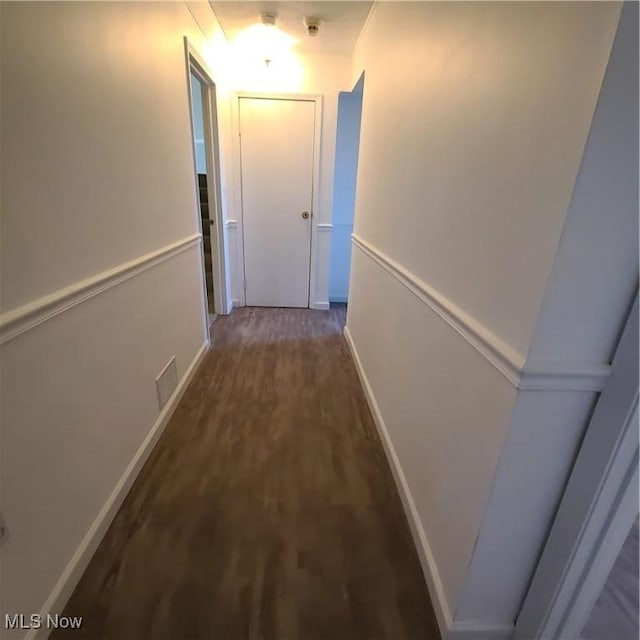 corridor featuring visible vents, baseboards, and wood finished floors