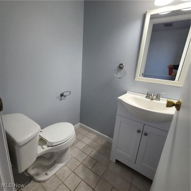 half bath featuring toilet, tile patterned floors, baseboards, and vanity