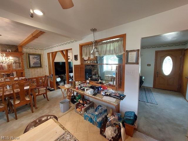 interior space featuring a fireplace, ceiling fan with notable chandelier, hanging light fixtures, tile floors, and beamed ceiling