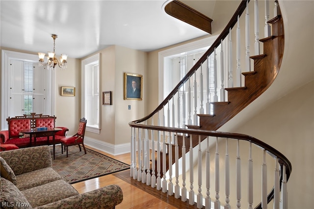 staircase with wood-type flooring and a chandelier