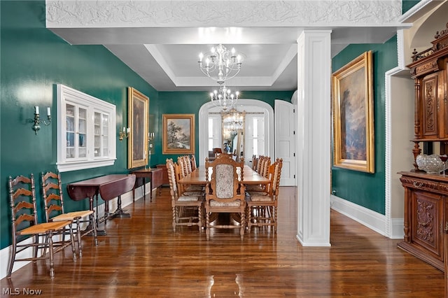 dining area with ornate columns, dark hardwood / wood-style flooring, a raised ceiling, and a notable chandelier