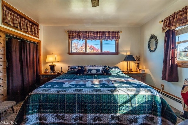 bedroom with ceiling fan, a baseboard radiator, and multiple windows