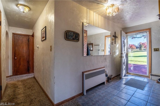 entrance foyer featuring radiator heating unit, carpet floors, and an inviting chandelier