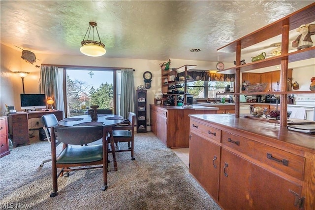 kitchen with a wealth of natural light, light carpet, sink, and decorative light fixtures