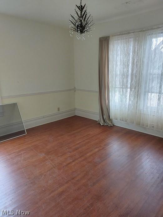 empty room featuring an inviting chandelier and dark hardwood / wood-style floors