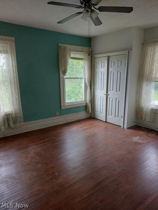 unfurnished bedroom with wood-type flooring, ceiling fan, and a closet