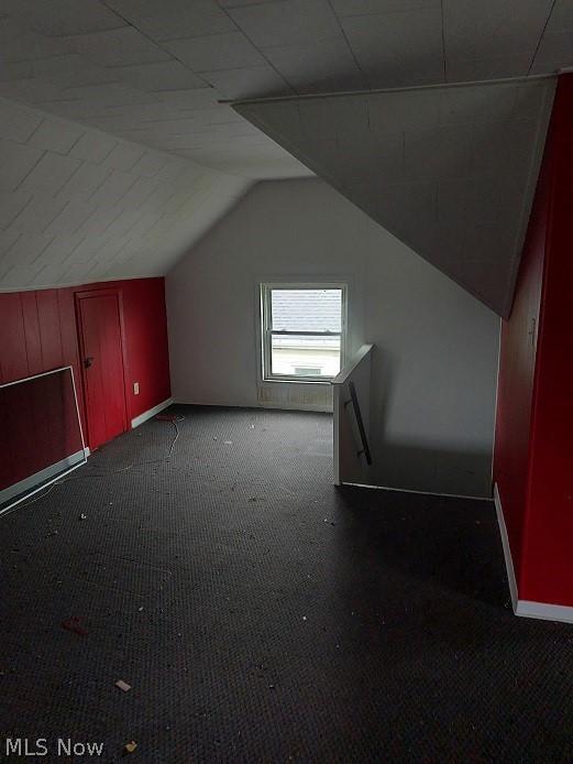 bonus room featuring vaulted ceiling and dark colored carpet