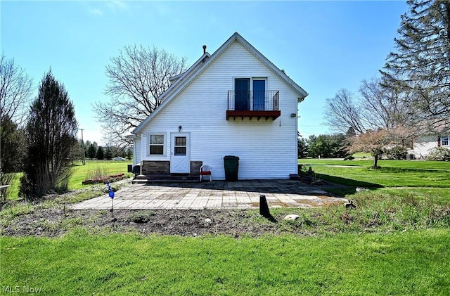 rear view of property with a balcony, a patio area, and a lawn