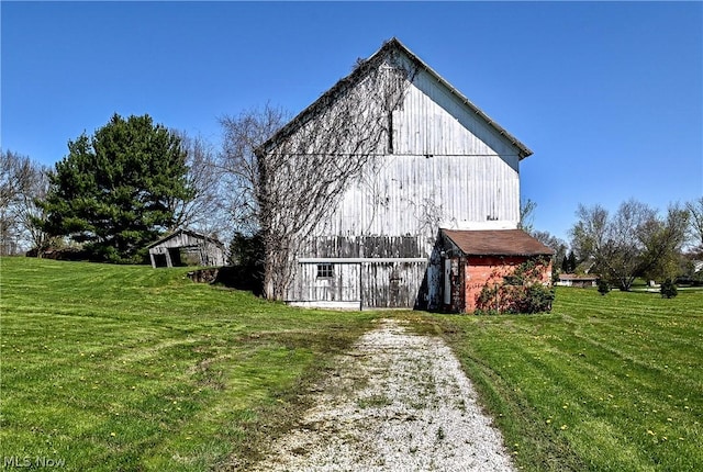 view of side of property with a lawn and an outbuilding