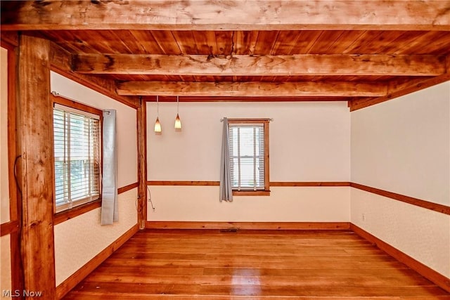 unfurnished room with beam ceiling, a wealth of natural light, hardwood / wood-style floors, and wooden ceiling