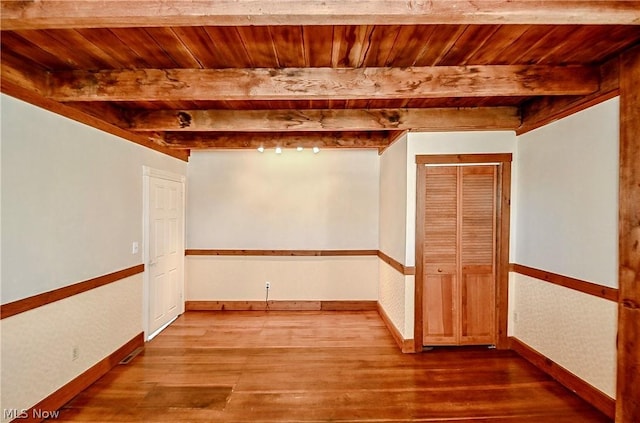 empty room featuring hardwood / wood-style floors, beam ceiling, and wooden ceiling