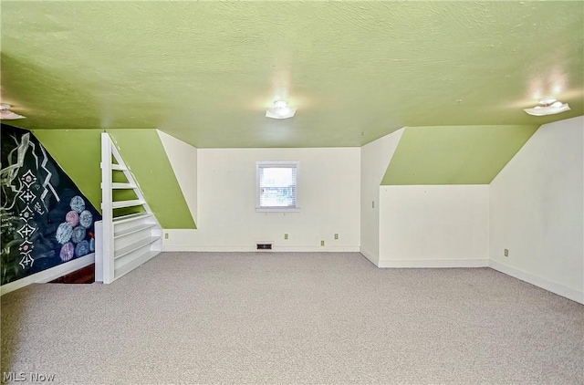 additional living space featuring carpet floors, a textured ceiling, and vaulted ceiling