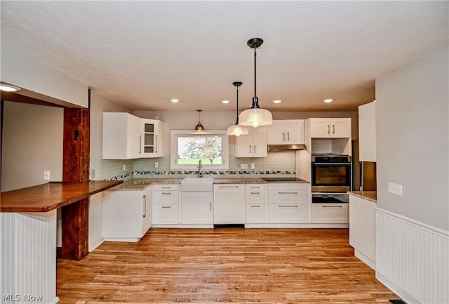 kitchen with white cabinets, oven, hanging light fixtures, and sink