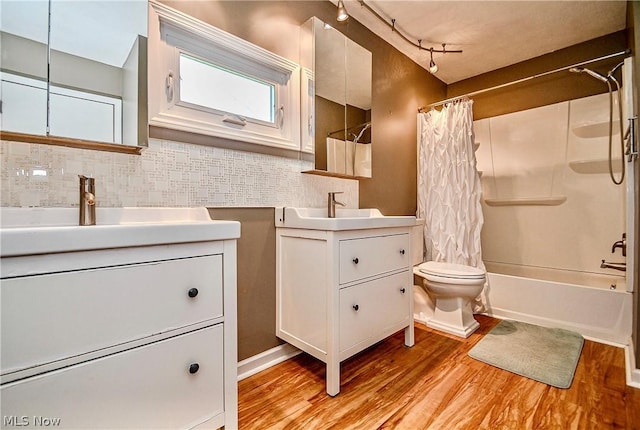 full bathroom with hardwood / wood-style floors, shower / bath combination with curtain, track lighting, decorative backsplash, and vanity