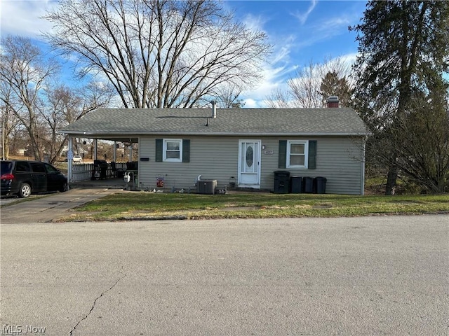 view of front of house with a front yard, a carport, and cooling unit