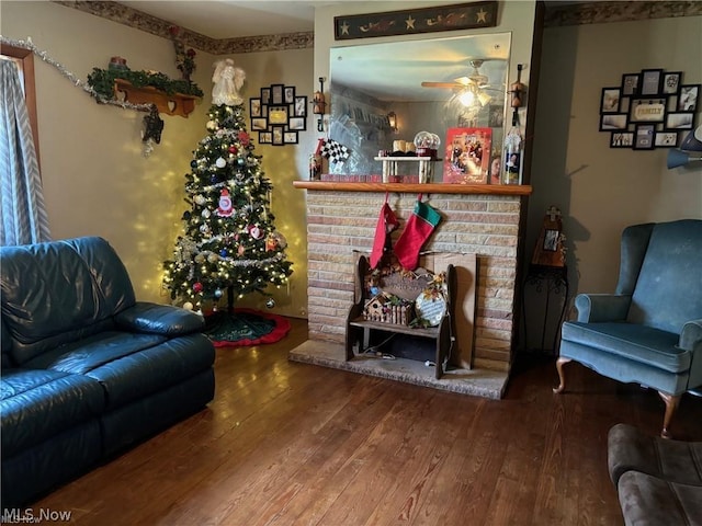 living room featuring hardwood / wood-style flooring, ceiling fan, and a fireplace