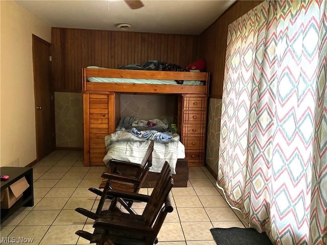 tiled bedroom with ceiling fan and wood walls