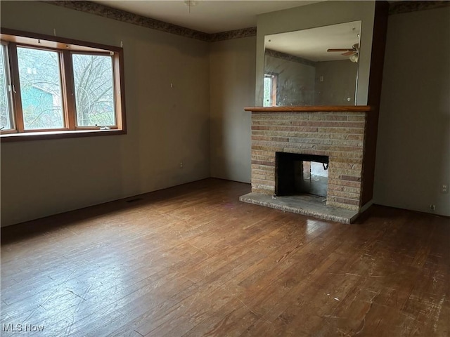 unfurnished living room with ceiling fan, wood-type flooring, and a fireplace