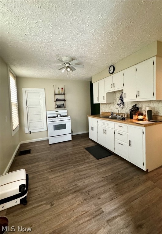 kitchen featuring gas range gas stove, ceiling fan, dark hardwood / wood-style flooring, and tasteful backsplash