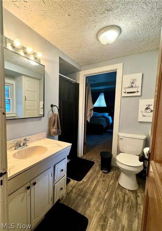 bathroom with hardwood / wood-style floors, vanity, toilet, and a textured ceiling