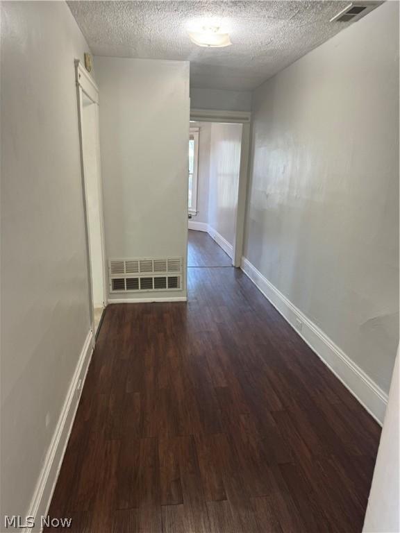 hallway featuring dark wood-type flooring and a textured ceiling