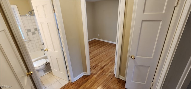 bathroom with shower / washtub combination, wood-type flooring, and toilet