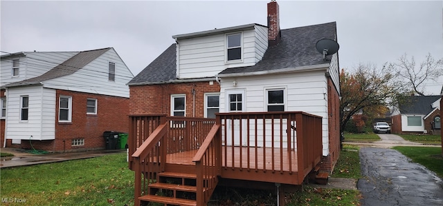 rear view of house featuring a lawn and a deck