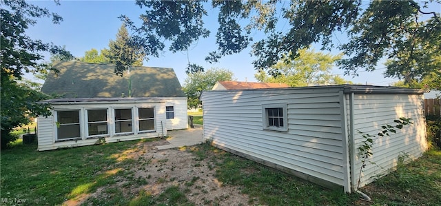 back of house featuring a lawn and an outbuilding