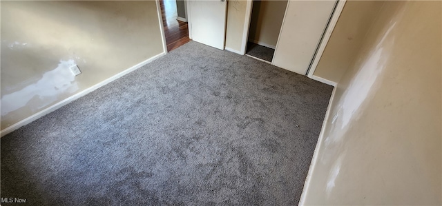 unfurnished bedroom with dark colored carpet and a closet